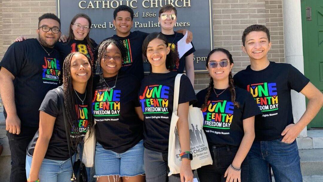 group of young people wearing black t shirts with colorful logos